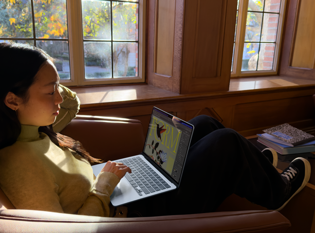 A person sitting in a chair using their MacBook Air