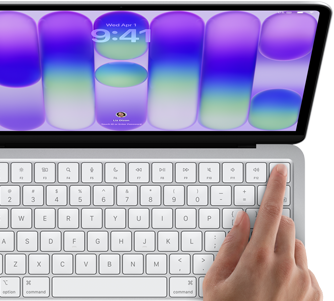 MacBook Neo, silver colour, showing login screen, person’s finger on Touch ID sensor in top-right corner of keyboard