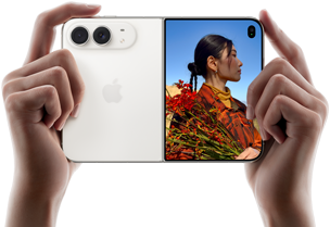 iPhone Duo, Star White colour, held by two hands in horizontal orientation, unfolded, left panel shows 48MP Dual Fusion rear cameras, right panel shows person getting their picture taken on outer display, the subject of the photo is able to see their face as their picture is getting taken using Duo Preview
