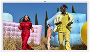 Three people in bright outfits, surrounded by colorful inflatable shapes