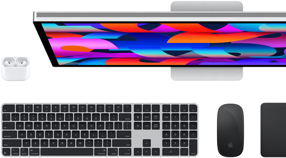 Top-down view of Studio Display monitor, black Magic Keyboard, black Magic Mouse, black Magic Trackpad and white AirPods case