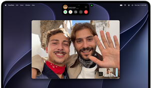 MacBook Pro with PROLED XDR Display, silver color, display shows a video call in progress with two people in a sunlit town waving to a person at home