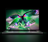 MacBook Pro with PROLED XDR Display, open lid, space black color, display shows detailed, high-contrast image with vivid colors, screen illuminates keyboard